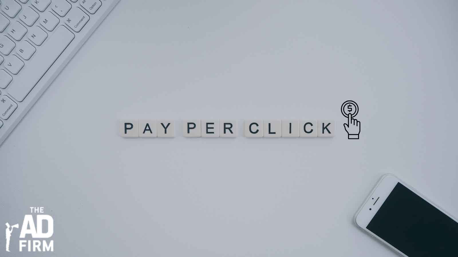 Pay Per Click spelled out with tiles alongside a keyboard and phone, highlighting strategic PPC strategies.