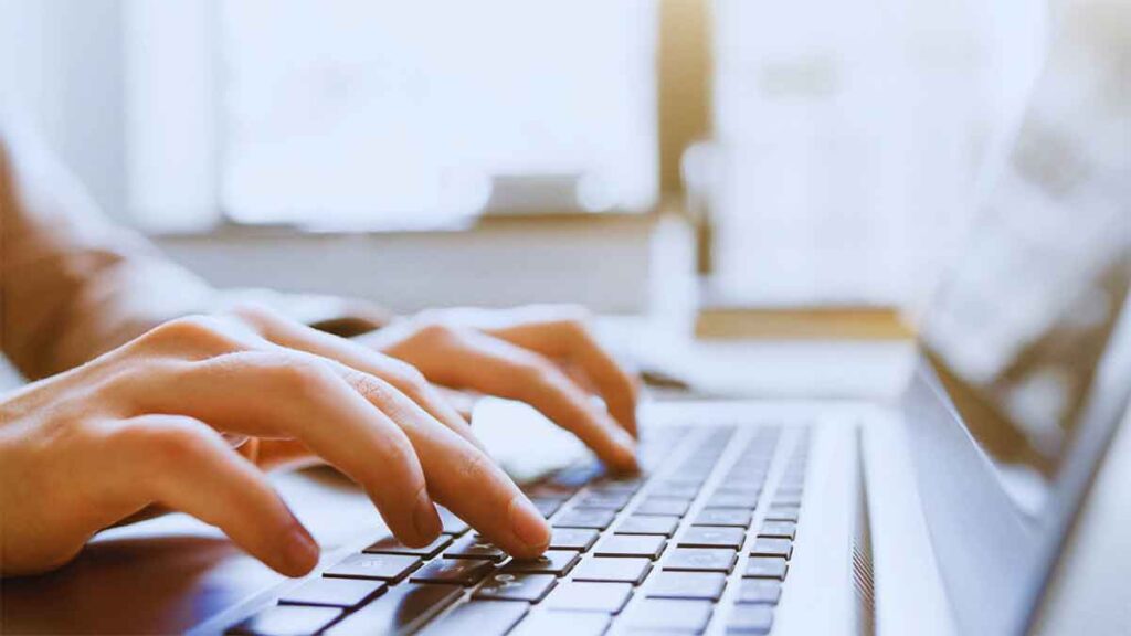 Close-up of hands typing on a laptop, illustrating content personalization in digital marketing strategies.
