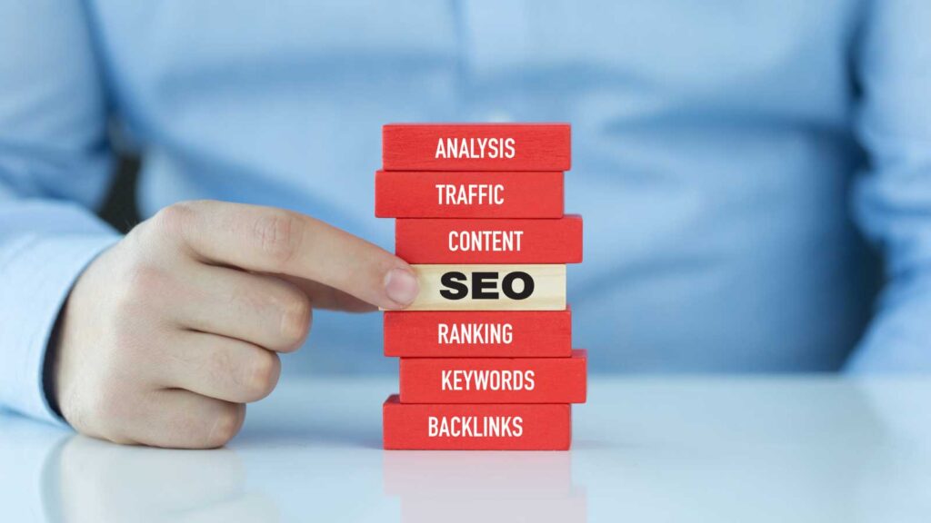  Hand pulling a block labeled SEO from a stack of digital marketing terms.