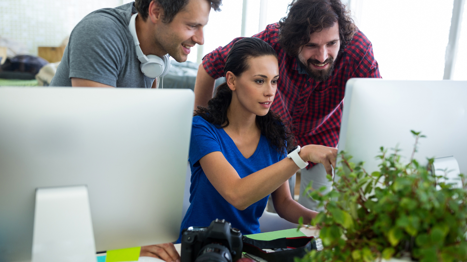 A marketing team brainstorming in front of a monitor screen