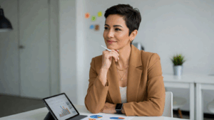 A confident businesswoman sits at a desk with charts and a digital tablet, representing strategic SEO planning for AI-driven search optimization.