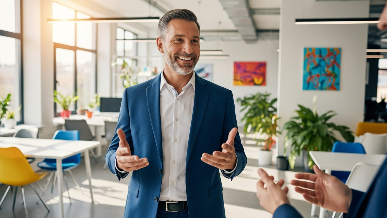 Confident business professional in a blue suit speaking with colleagues in a bright, modern office, representing corporate-franchise collaboration.