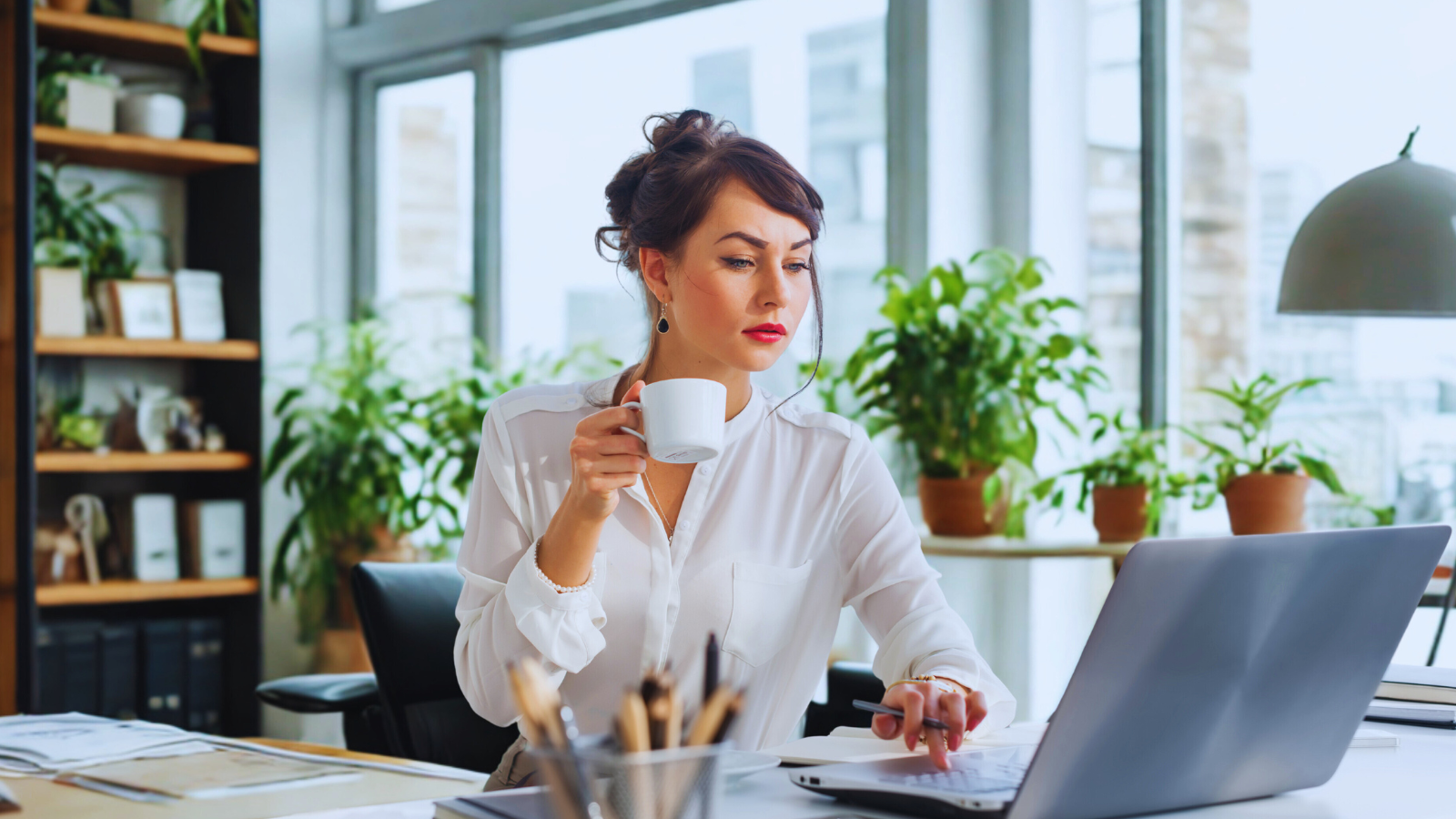 Professional woman working on a laptop with a cup of coffee, diligently optimizing AI data structured content for better ranking.