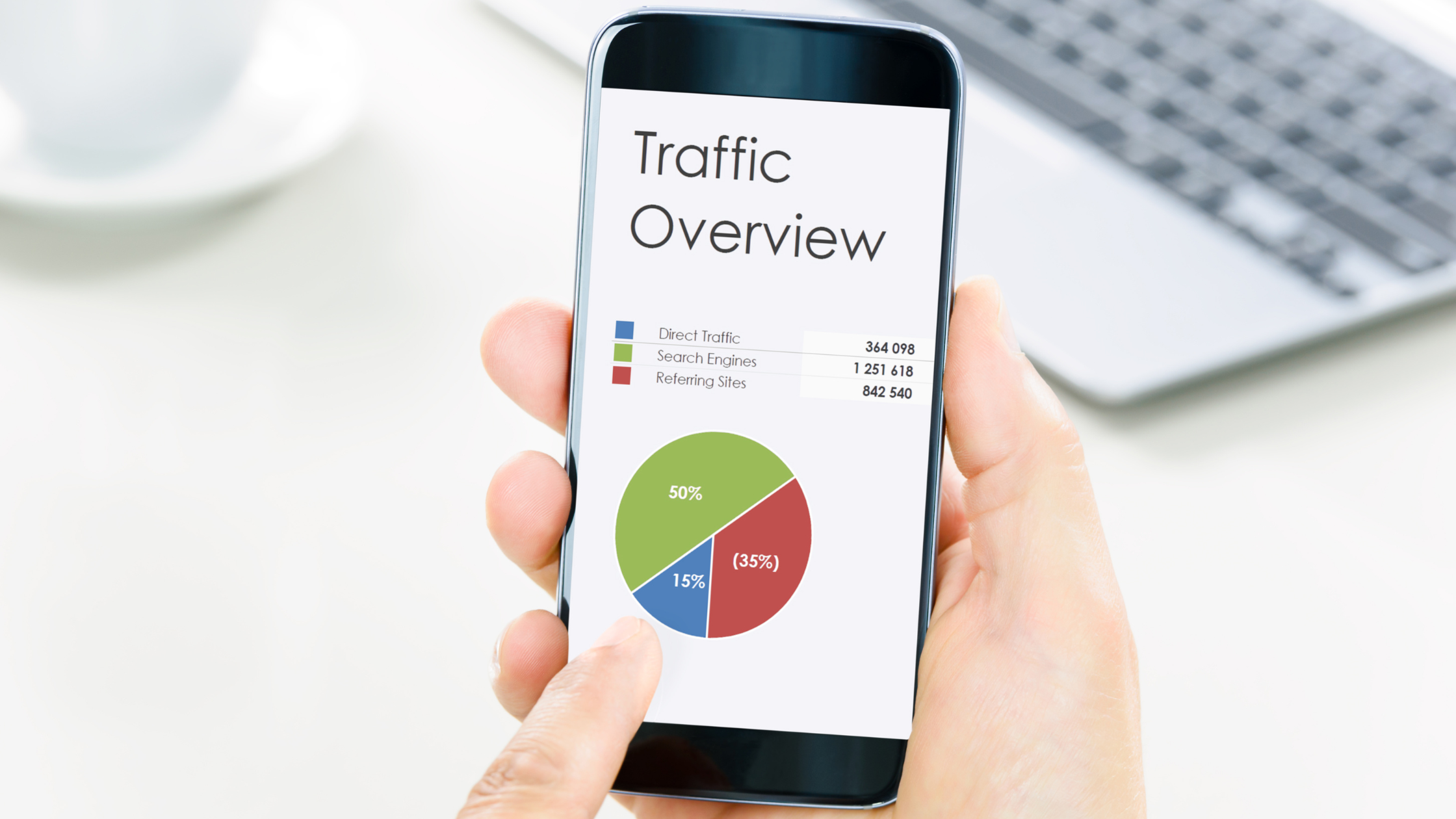 A man holding a smartphone displaying SEO traffic stats 