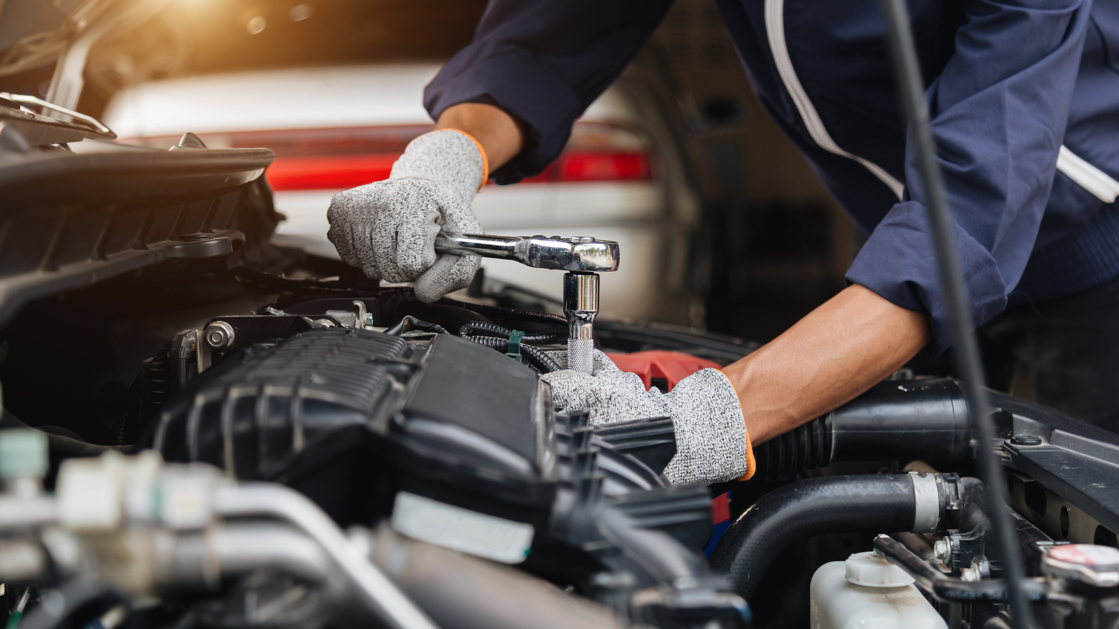 Mechanic uses a ratchet to work on a car engine