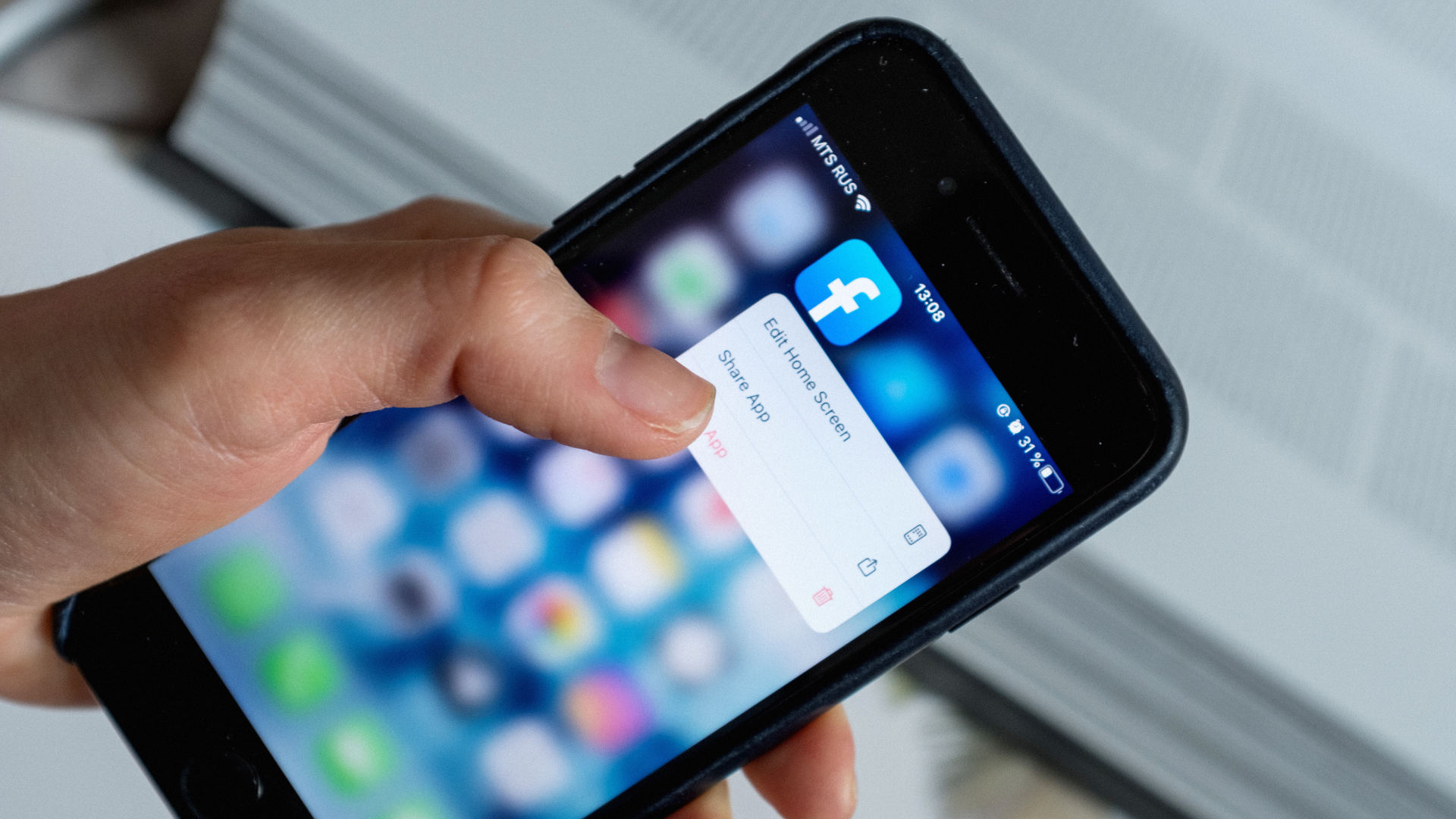 A man using his phone while the Facebook icon is visible on the screen