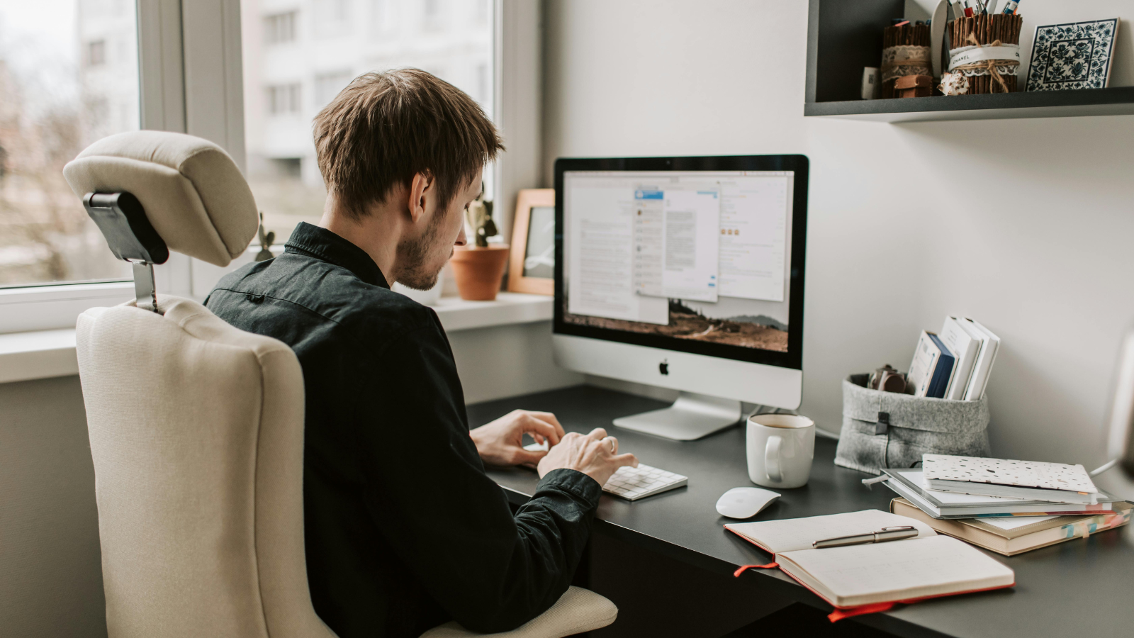 A man works on a computer at a home office desk