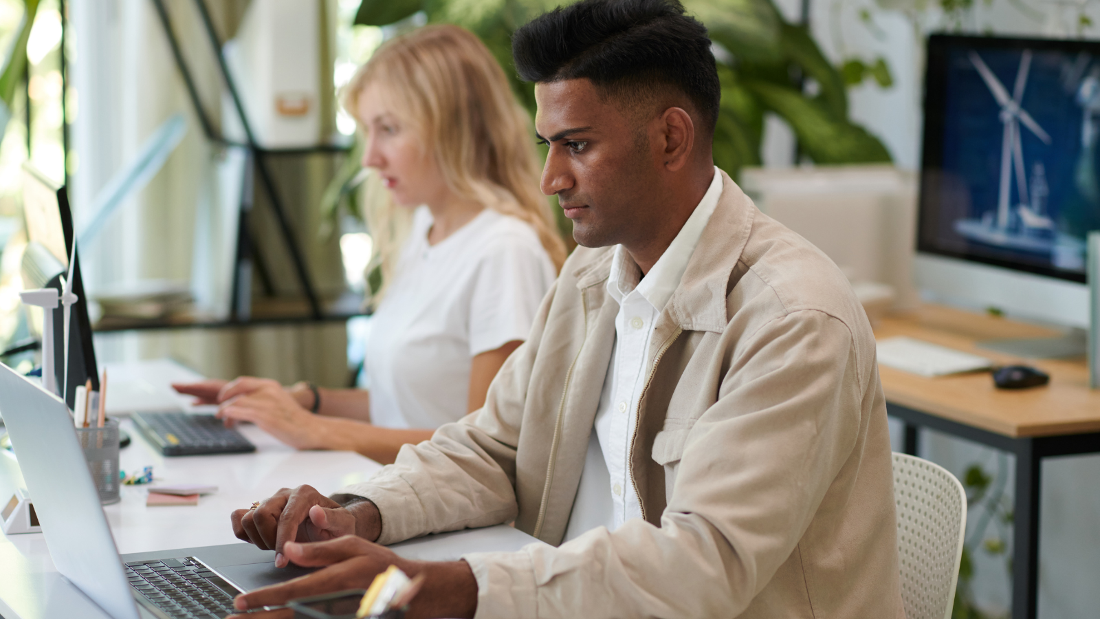 Two people working on laptops in a modern office space