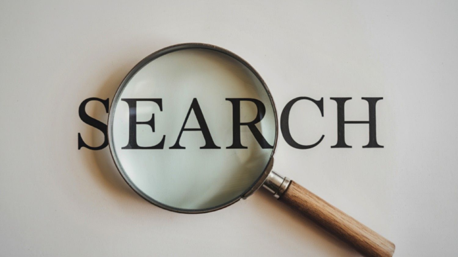 Magnifying glass highlighting the word “SEARCH”