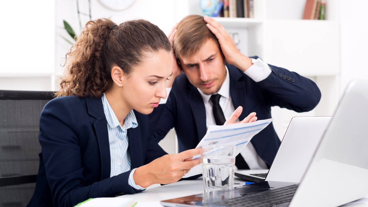 Two professionals in an office looking concerned