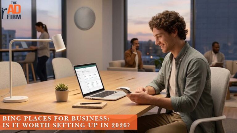 Business owner using a smartphone beside a laptop displaying an online business listing dashboard.